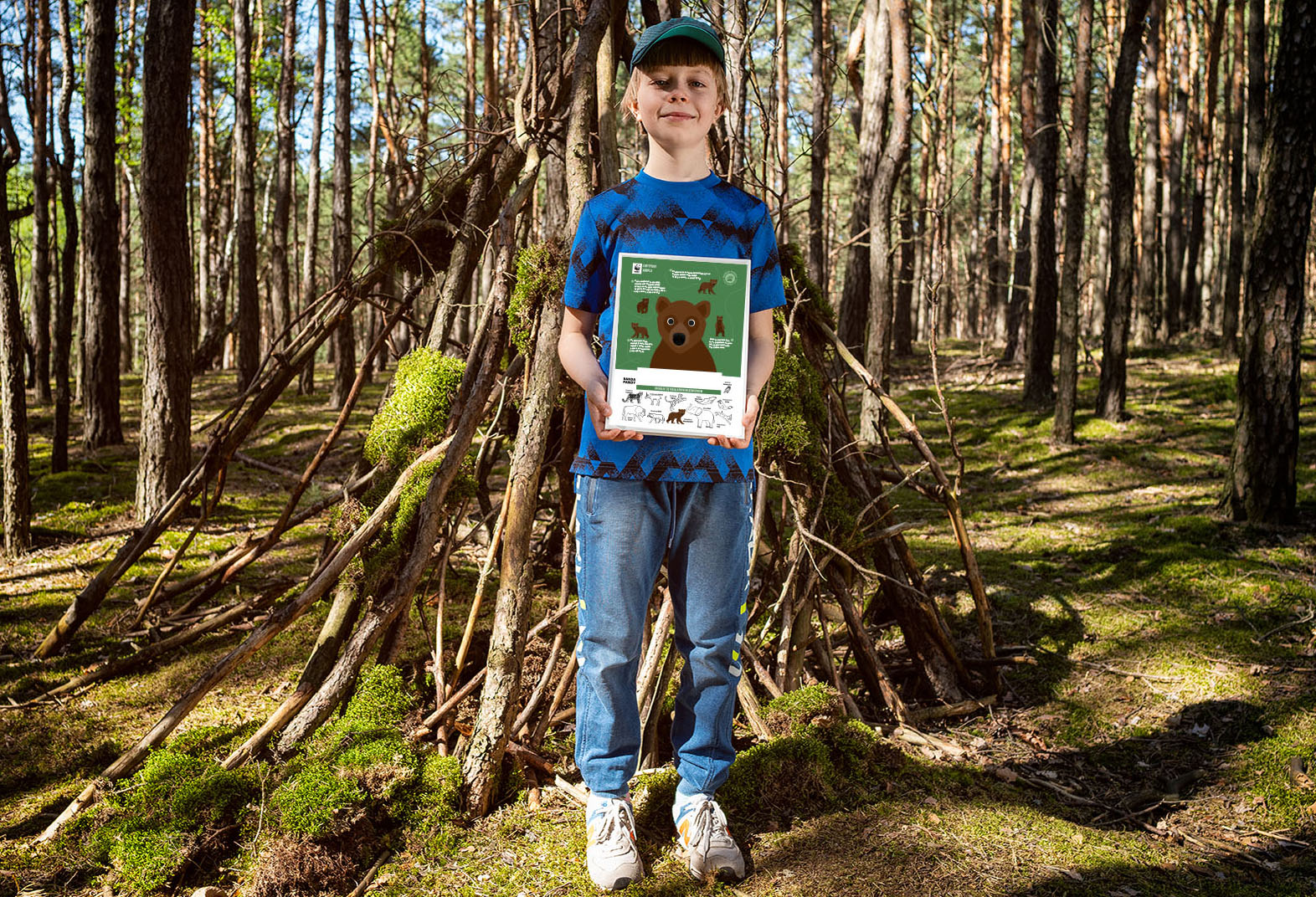 Chłopiec stojący w lesie trzyma certyfikat adopcji niedźwiedzia